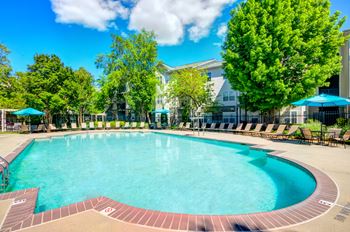 a swimming pool with trees and a building in the background